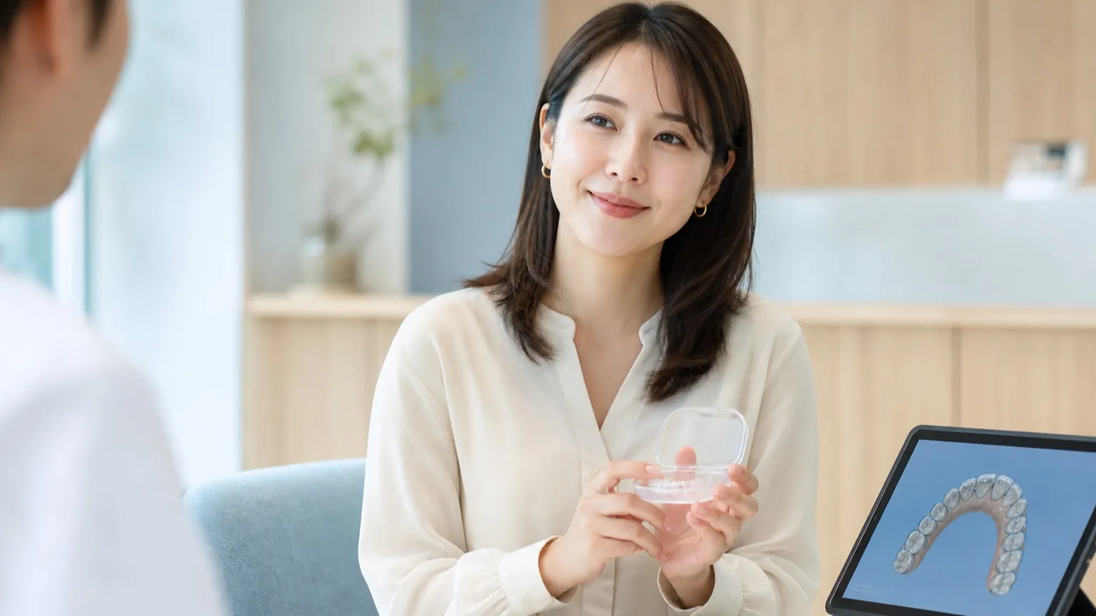 矯正治療後の前歯のすき間と開咬について、リテーナーを持参して再相談する成人女性