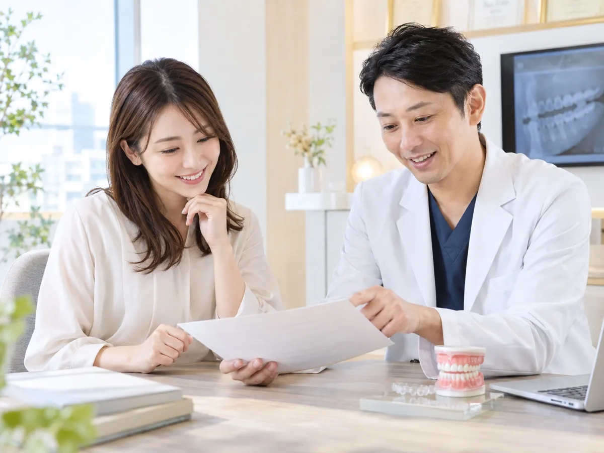 矯正治療の費用について、歯列模型と見積書を見ながら説明を受ける成人女性